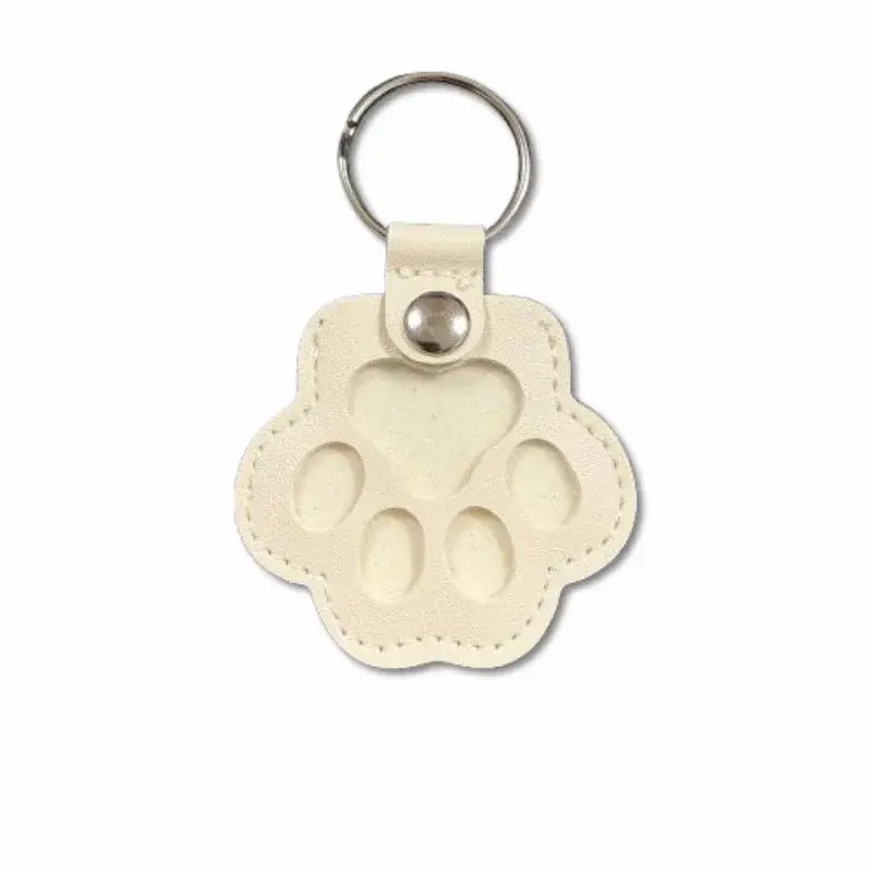 Cream-colored leather paw print keychain with stitched edges and silver metal ring for pet fur memorial keepsake storage