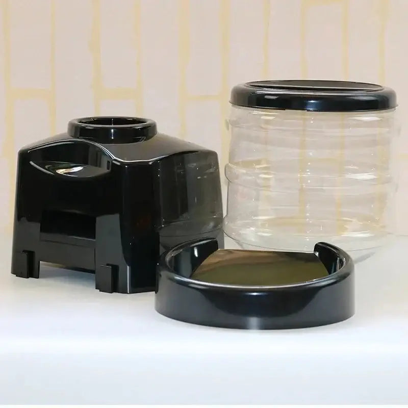 Black plastic automatic timed pet food dispenser with clear water reservoir and matching black lid for pets