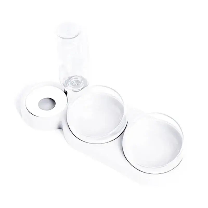 Clear plastic automatic triple bowl pet feeder with three circular compartments and small bottle in background