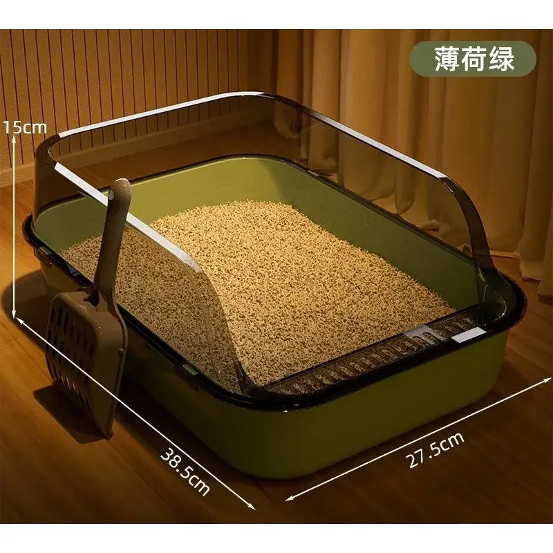 Green plastic cat litter box with transparent side panel and black trim filled with beige granular litter for pets outside