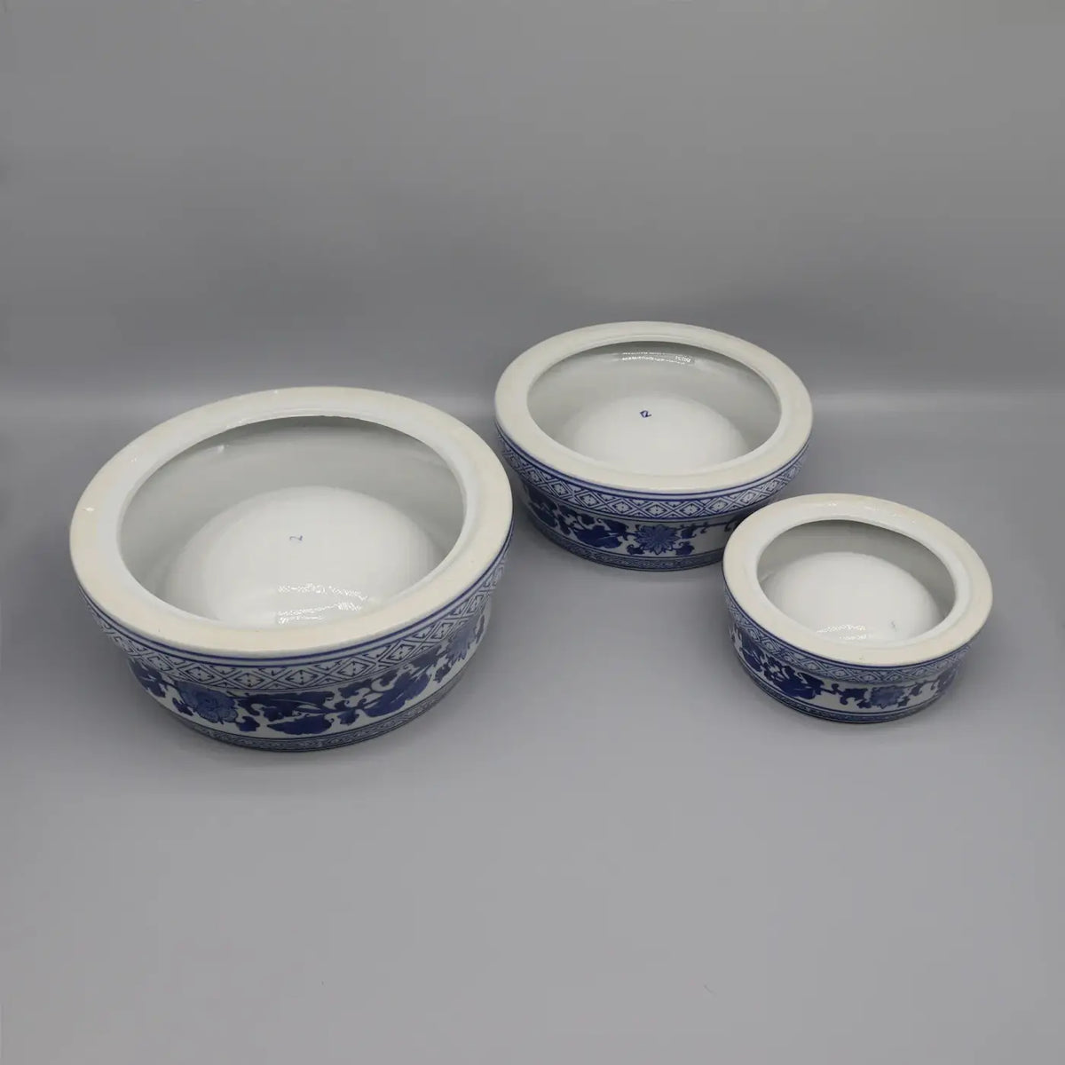 Three ceramic pet feeding bowls with blue and white floral patterns and clear glass lids for pet meals