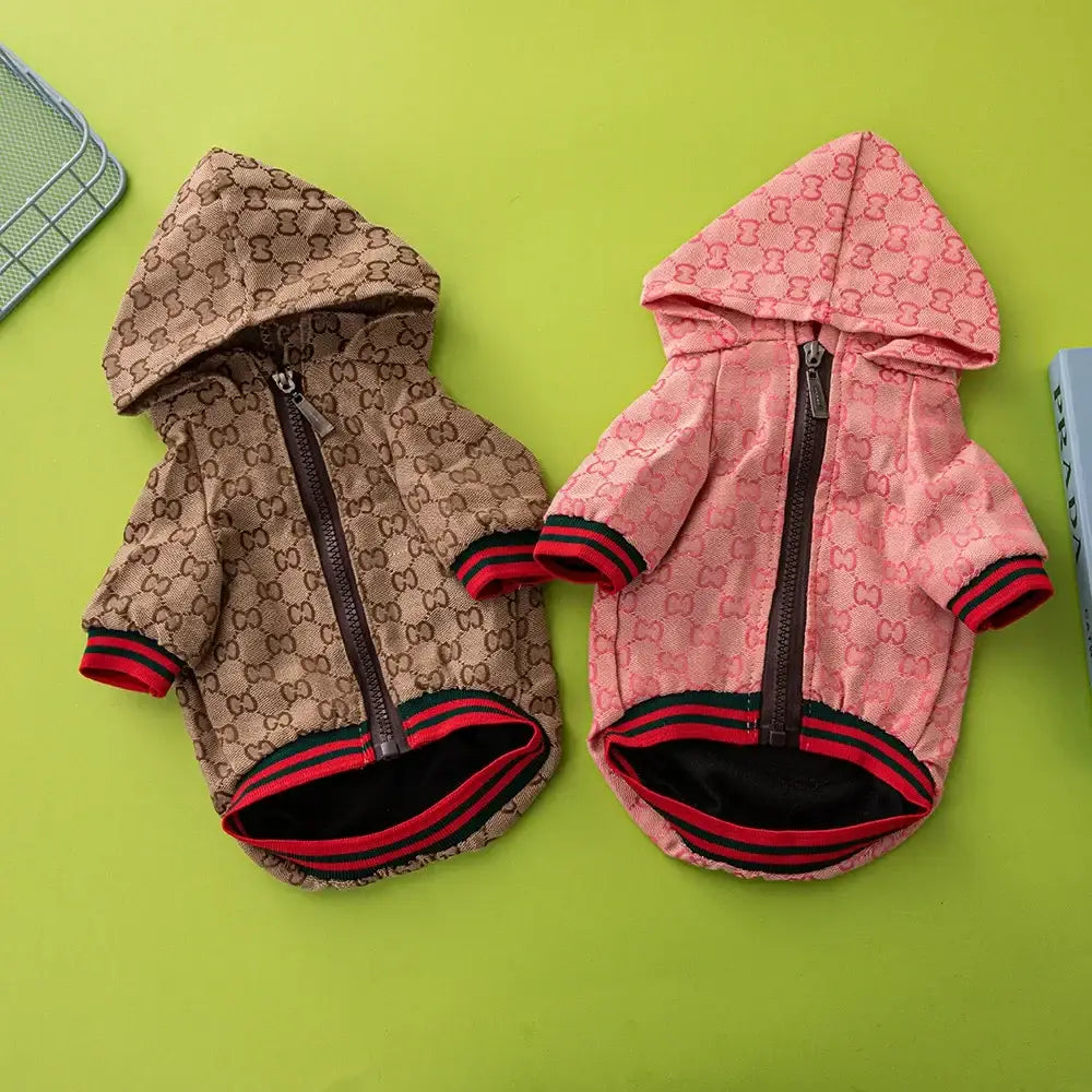 Two gucci-style hooded pet jackets in beige with brown monogram and pink with red and black trim luxury dog coats