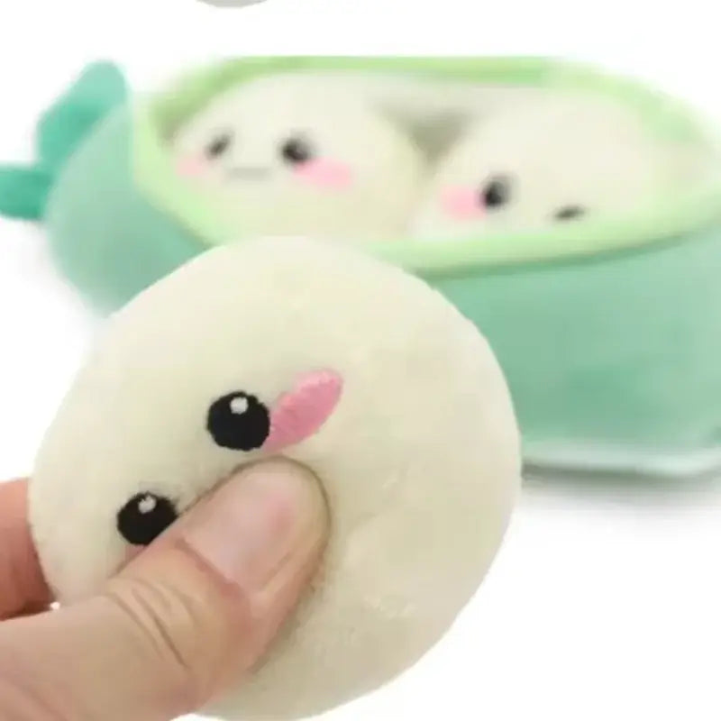 Cream-colored plush squishy dumpling dog toy with black button eyes and pink tongue from pea pod pet toys interactive puzzle toy