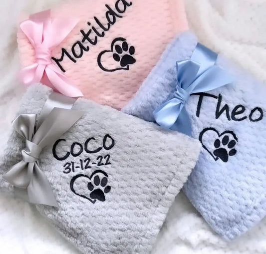 Personalized embroidered paw print pet blankets in pink blue and gray with satin bows and names on soft fabric