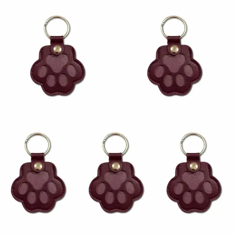 Maroon leather paw print keychains with gold tone rings and rivets for pet fur memorial keepsake and hair storage bag