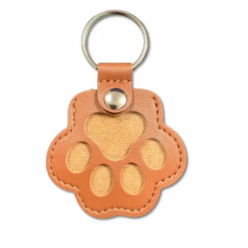 Tan leather pet fur memorial keepsake keychain shaped like a paw print with cut-out toe pads and heart center