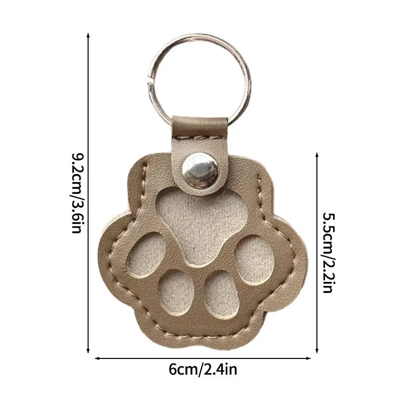 Beige leather paw-shaped pet fur memorial keepsake keychain with stitched edges and silver metal ring for hair storage