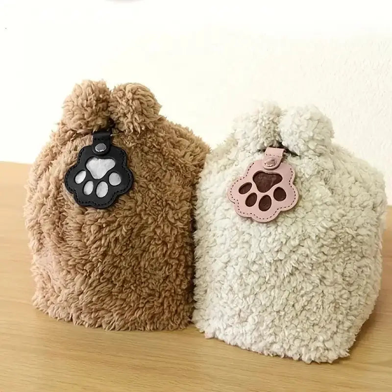 Two fluffy pet fur memorial keepsake keychain pouches in tan and off-white with paw-print charms and soft textured surface