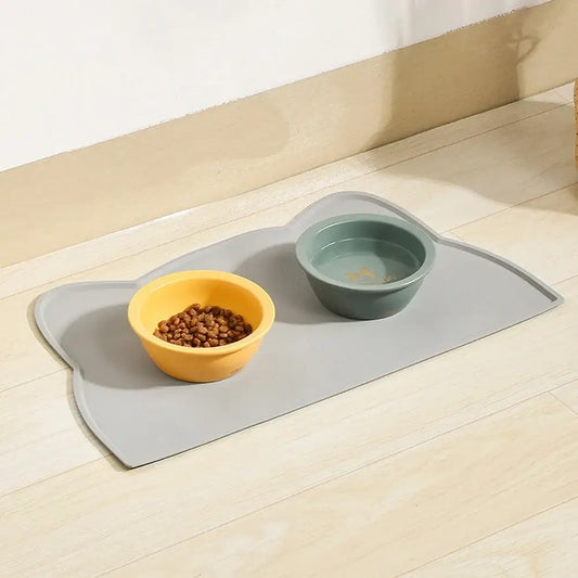 Gray silicone cat-shaped waterproof non-slip pet food placemat with two bowls one yellow and one green