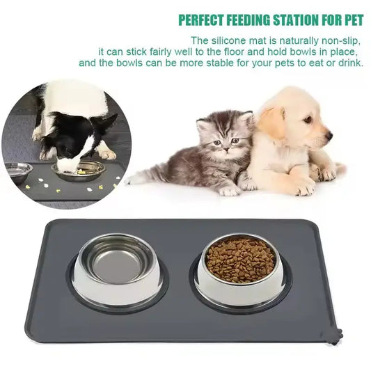 Gray waterproof silicone pet feeding mat with two stainless steel bowls one empty and one filled with kibble